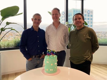 David Braham, Nick Hindhaugh and Paul Hallam, Founders of Six Degrees Executive, standing in front of a cake for the business 20th year anniversary