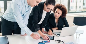 3 people looking at pie chart together in an office