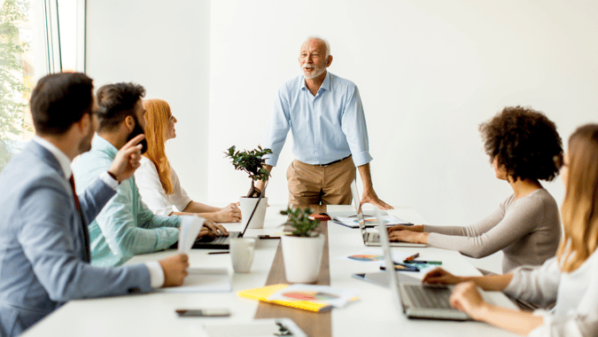 image of a professional leader standing in front of a meeting table with his team