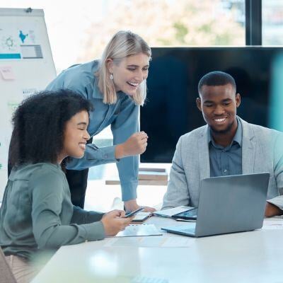 three accounting & finance professionals working together around a table and looking at a screen with a white board in the back