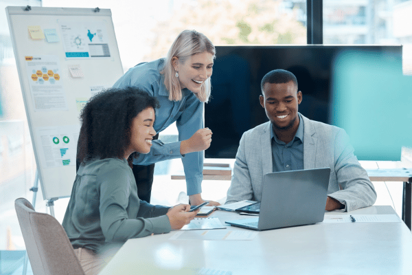 three accounting and finance professionals working together around a table and looking at a screen with a white board in the back