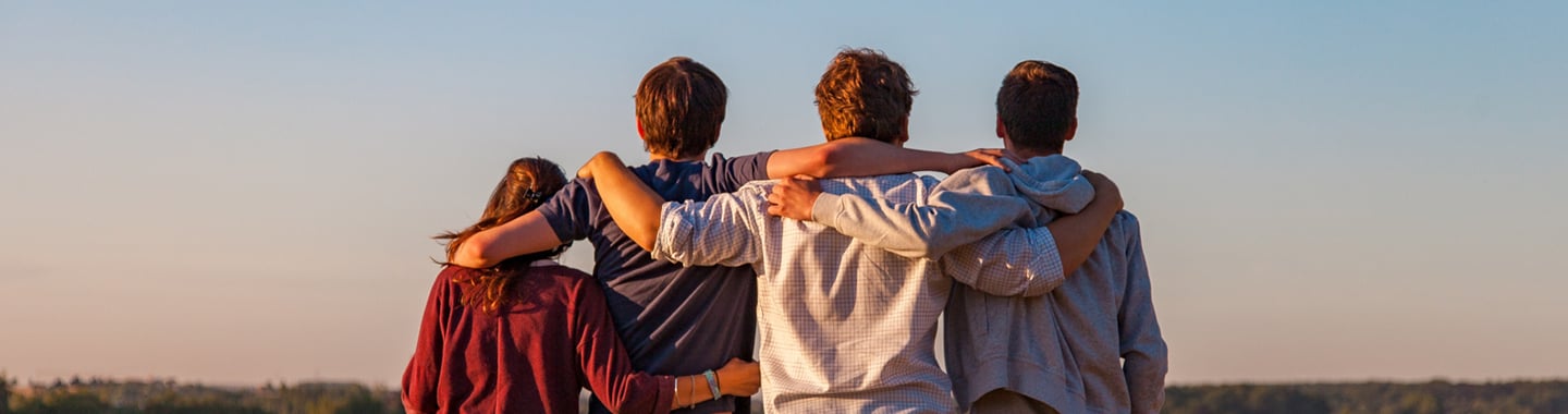 4 young people holding each other by the shoulders