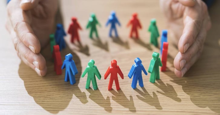 Pair of hands around group of multicoloured figurines