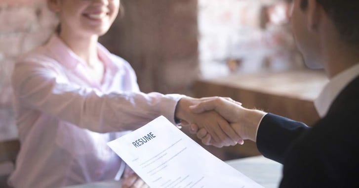 2 people shaking hands over a CV