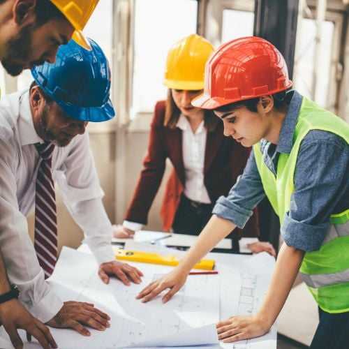 4 construction employees looking at a floor plan together