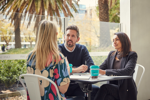 two women and a man sitting down at the terrasse of a cafe.